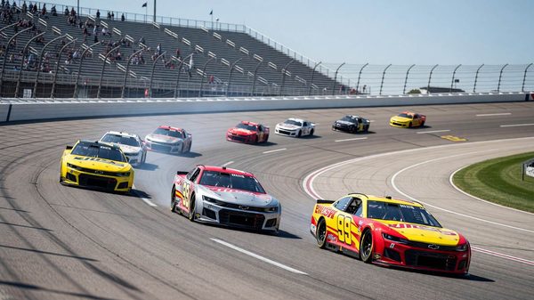 Stock car racing at speed on an oval track banking under bright summer daylight